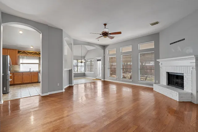 a view of an empty room with wooden floor and a fireplace