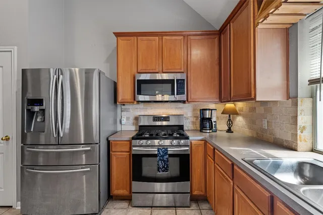 a kitchen with refrigerator a microwave a sink and cabinets
