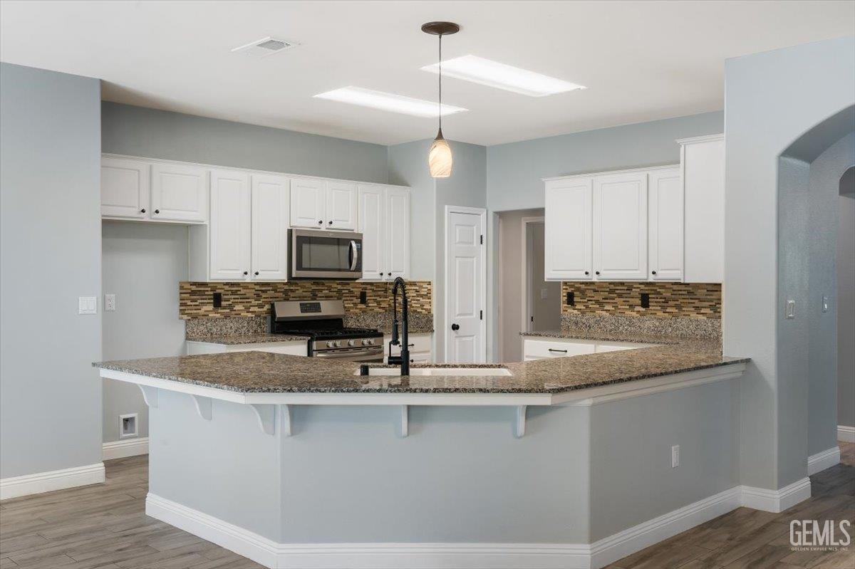 Undisclosed Address Bakersfield, CA 93312 - Photo 33 of 45 a kitchen with kitchen island granite countertop a sink and microwave