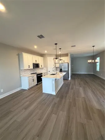 a large kitchen with cabinets wooden floor and stainless steel appliances