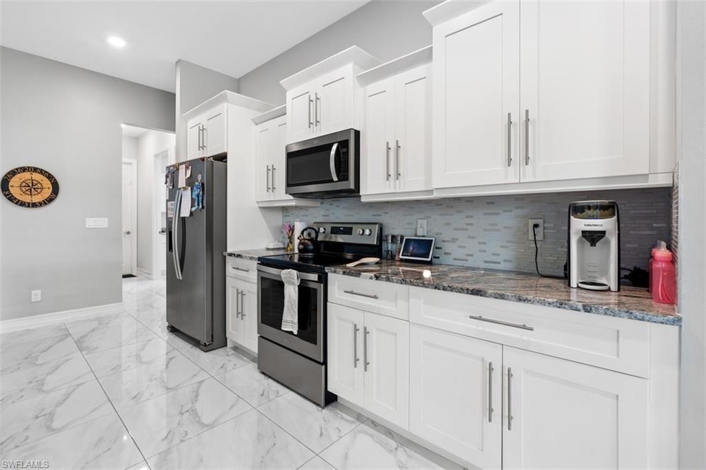 3611 8th Street Southwest Lehigh Acres, FL 33976 - Photo 5 of 21 a kitchen with stainless steel appliances granite countertop a sink a stove a microwave and a refrigerator