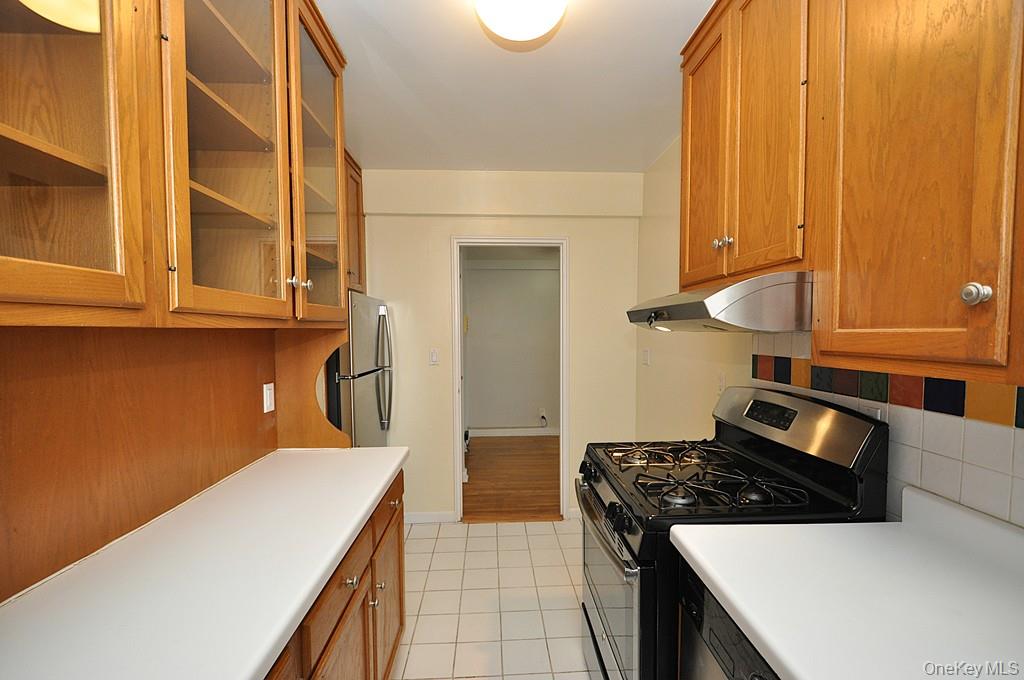 142 Garth Road, Unit 5S Scarsdale, NY 10583 - Photo 15 of 40 a kitchen with granite countertop a stove and a wooden cabinets