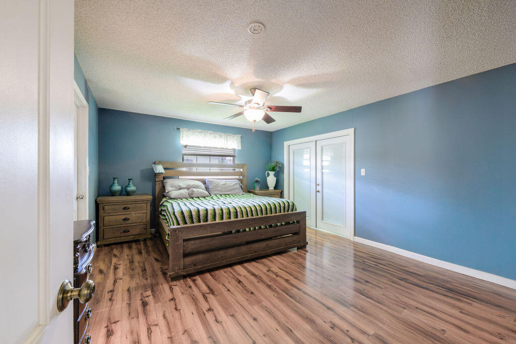 1044 4th Street Okeechobee, FL 34974 - Photo 15 of 39 a spacious bedroom with a bed and a chandelier