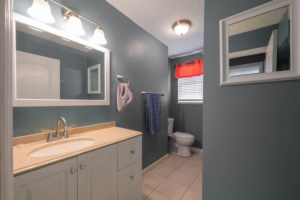 1044 4th Street Okeechobee, FL 34974 - Photo 23 of 39 a bathroom with a toilet sink and mirror