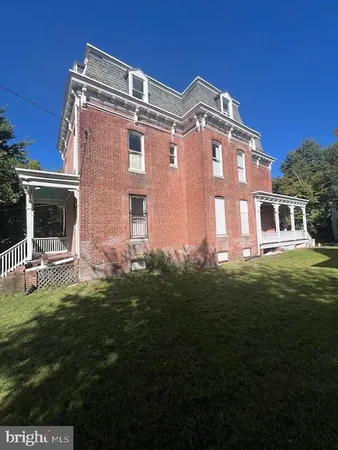 a view of a house with a big yard plants and large trees