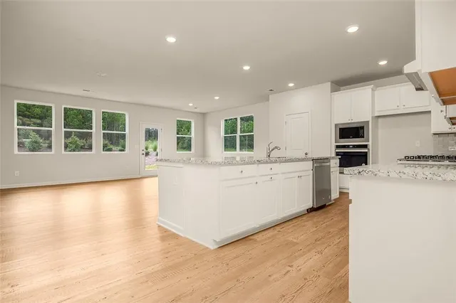 a large white kitchen with kitchen island a stove a sink a refrigerator and a cabinets