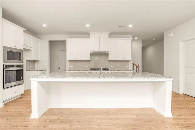 a view of kitchen with granite countertop stainless steel appliances and sink