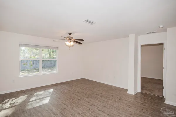 an empty room with wooden floor and windows