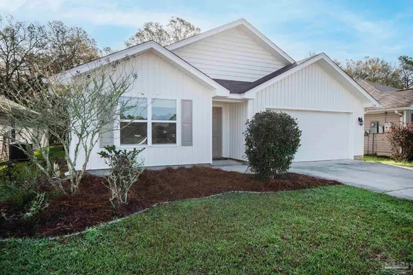 a view of a yard in front of a house with plants and large tree