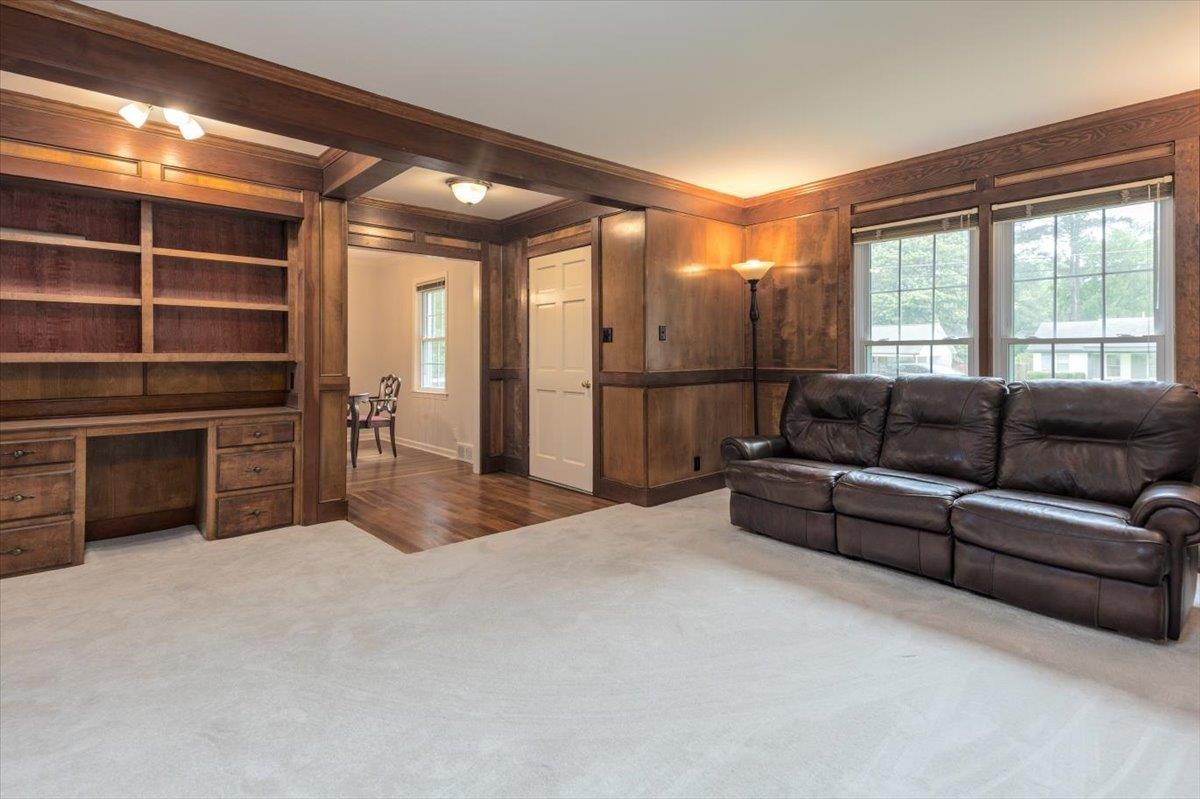 670 Peterson Lake Road Collierville, TN 38017 - Photo 13 of 37 Spacious room featuring extensive wood paneling and trim, a built-in desk with shelving and drawers, multiple windows, and light-colored carpeting