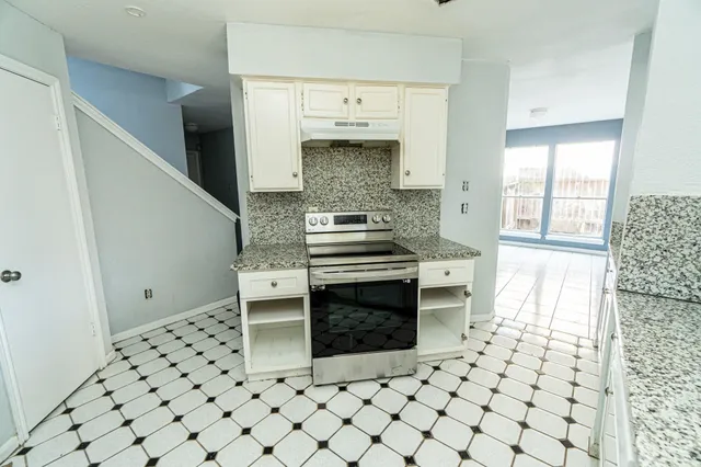 a kitchen with granite countertop a stove a microwave and a refrigerator