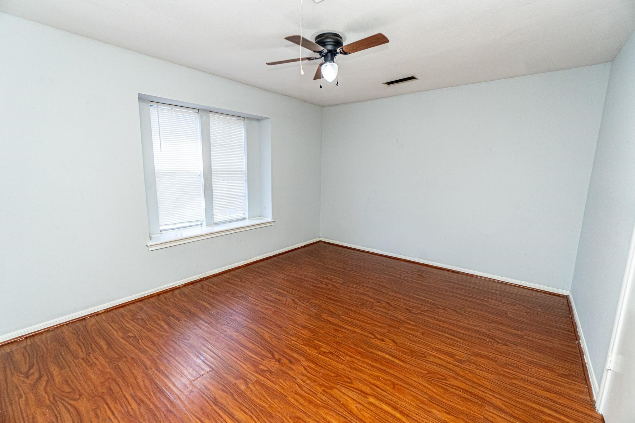 10903 Nobility Drive Houston, TX 77099 - Photo 6 of 12 an empty room with wooden floor ceiling fan and windows