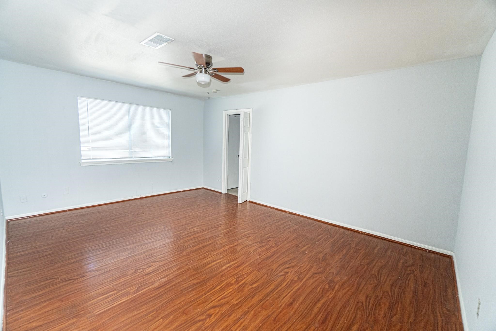 10903 Nobility Drive Houston, TX 77099 - Photo 9 of 12 an empty room with wooden floor ceiling fan and windows