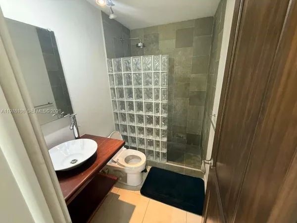 a bathroom with a sink a toilet a mirror and shower