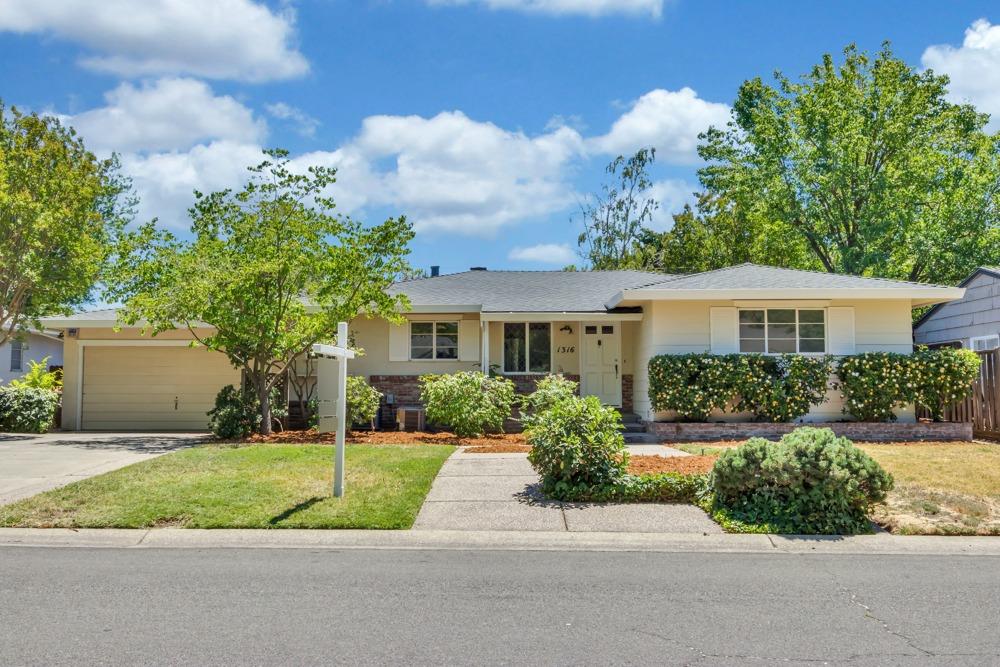 a front view of a house with a yard and potted plants