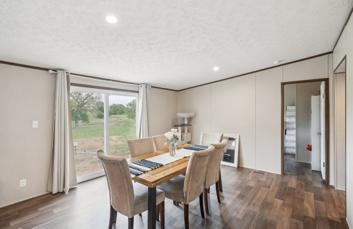 989 Ferguson Loop Dale Dale, TX 78616 - Photo 14 of 21 Dining area with a textured ceiling, dark wood-style floors, recessed lighting, and ornamental molding