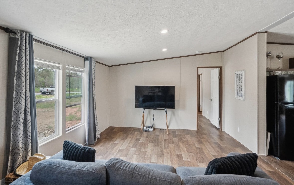 989 Ferguson Loop Dale Dale, TX 78616 - Photo 8 of 21 Living area featuring light wood-style floors, crown molding, and a textured ceiling