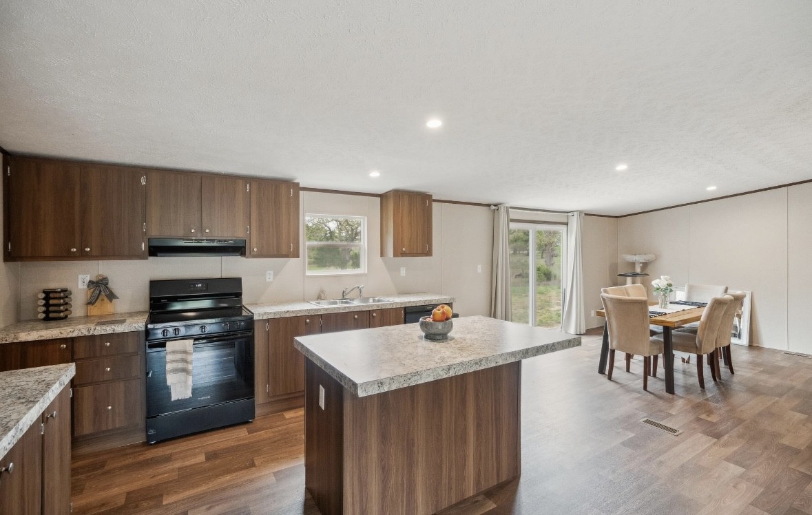 989 Ferguson Loop Dale Dale, TX 78616 - Photo 9 of 21 Kitchen with black range with electric stovetop, a kitchen island, dark wood-style flooring, light countertops, and recessed lighting