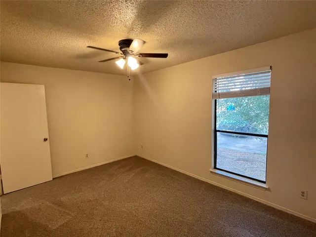 an empty room with a window and a fan
