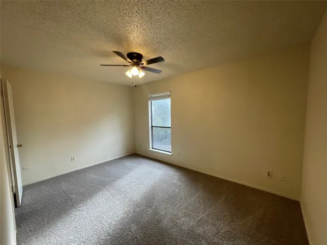 an empty room with a chandelier fan and windows