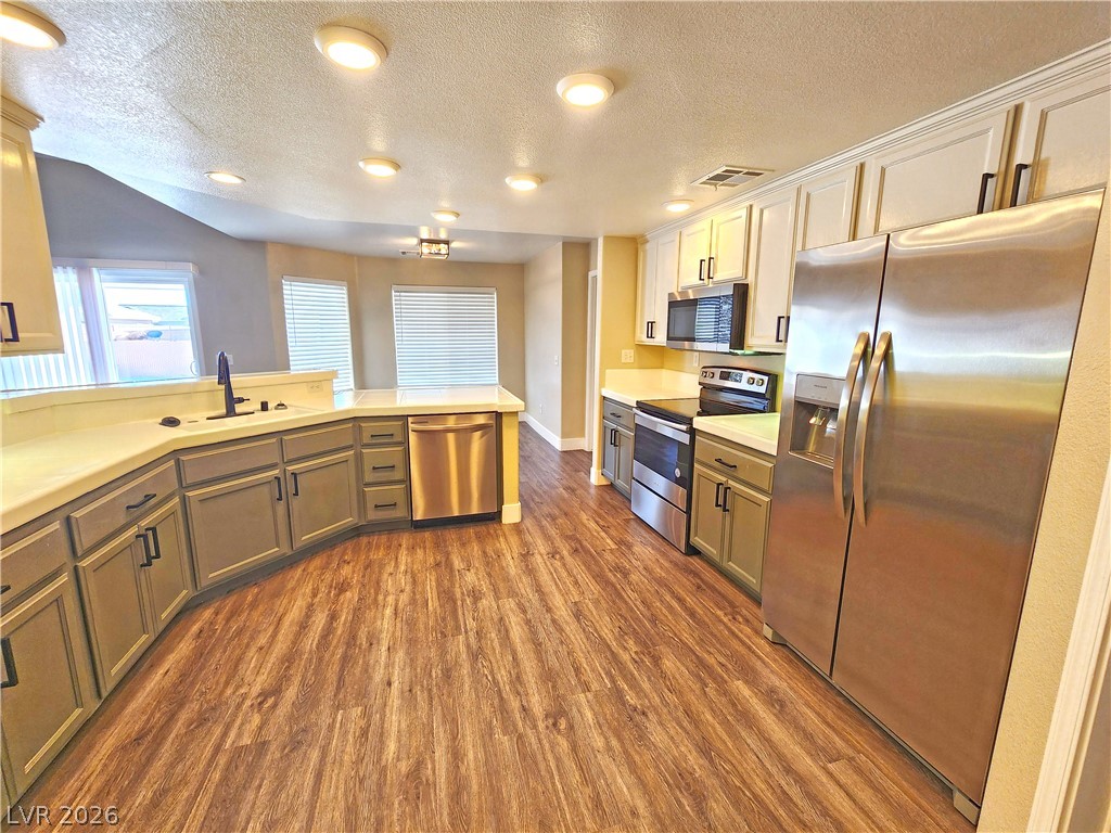4591 Stoneham Street Pahrump, NV 89061 - Photo 15 of 42 A contemporary kitchen features sleek countertops, rich wood flooring, and stainless steel appliances, creating an inviting space.
