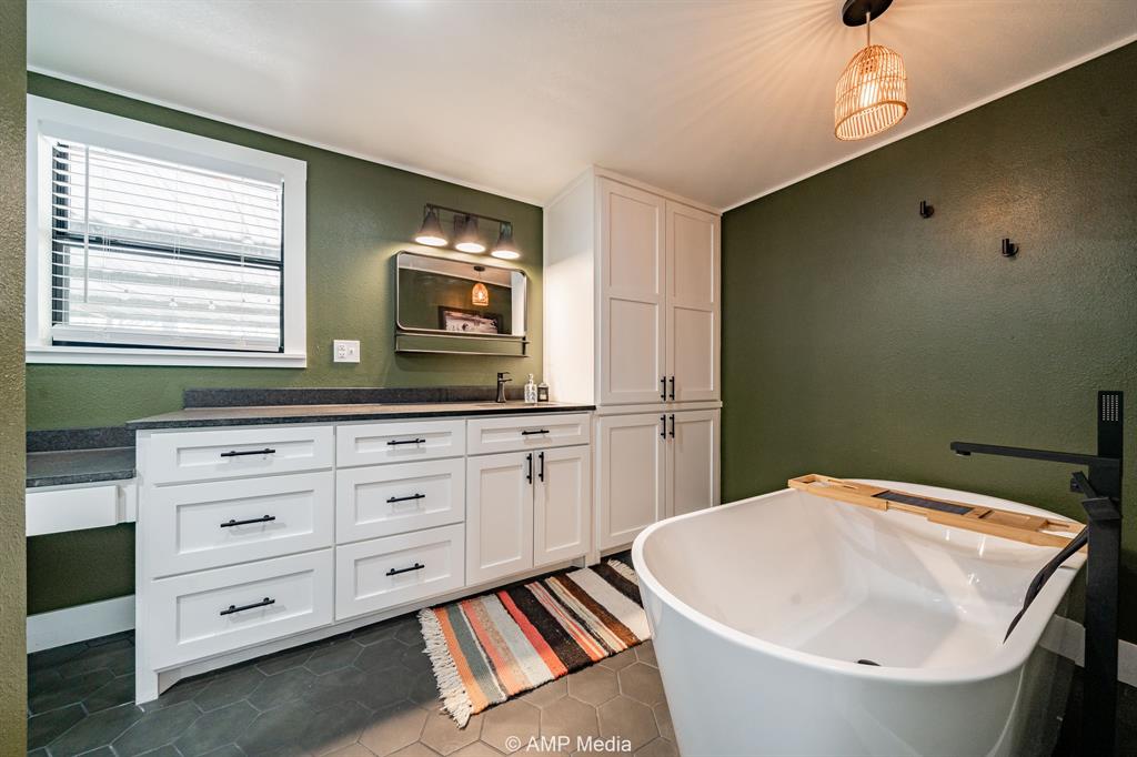 1002 Maple Street Stamford, TX 79553 - Photo 19 of 40 a bathroom with a sink a mirror and a bathtub