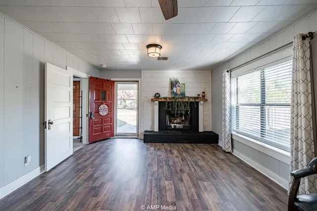 a view of an empty room with a window and wooden floor