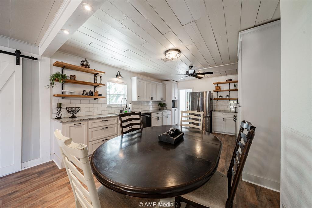 1002 Maple Street Stamford, TX 79553 - Photo 8 of 40 a kitchen with stainless steel appliances granite countertop a sink a refrigerator and wooden floor