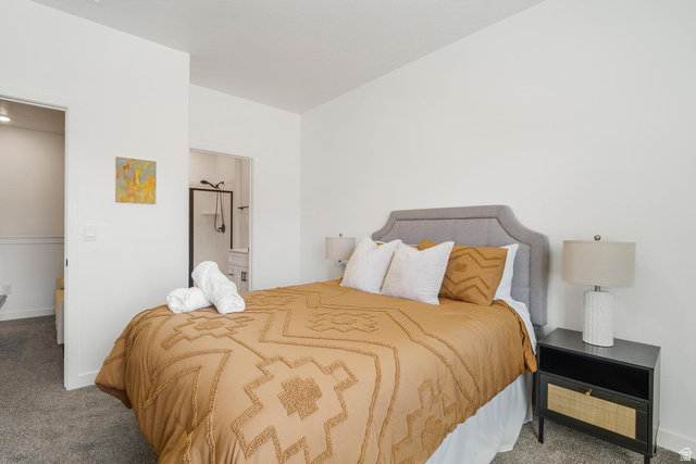 1705 Ripple Rock Drive, Unit 3017 Washington, UT 84780 - Photo 12 of 22 Carpeted bedroom with a gray upholstered headboard, white walls, and a black nightstand featuring a cane-front drawer