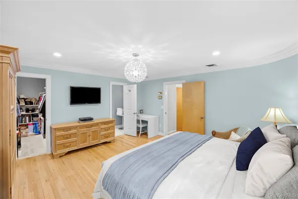 a spacious bedroom with a bed and a flat screen tv