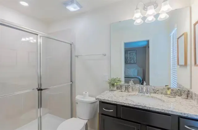 a bathroom with a granite countertop sink a toilet and a mirror