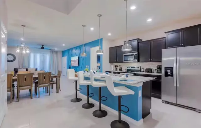 a kitchen with stainless steel appliances granite countertop a table chairs and a refrigerator