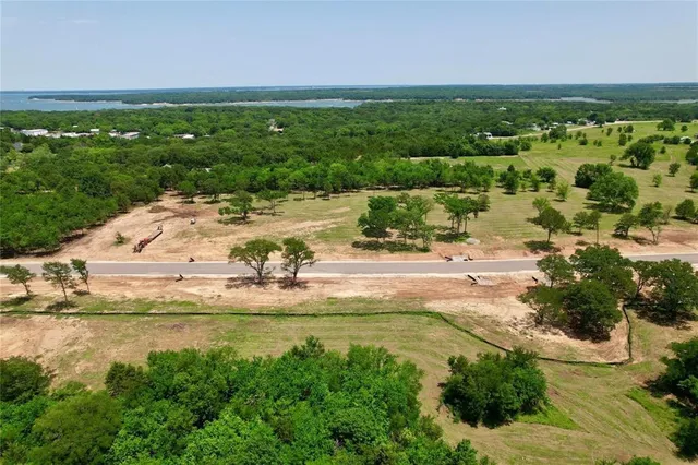 an aerial view of a residential houses with outdoor space and trees all around
