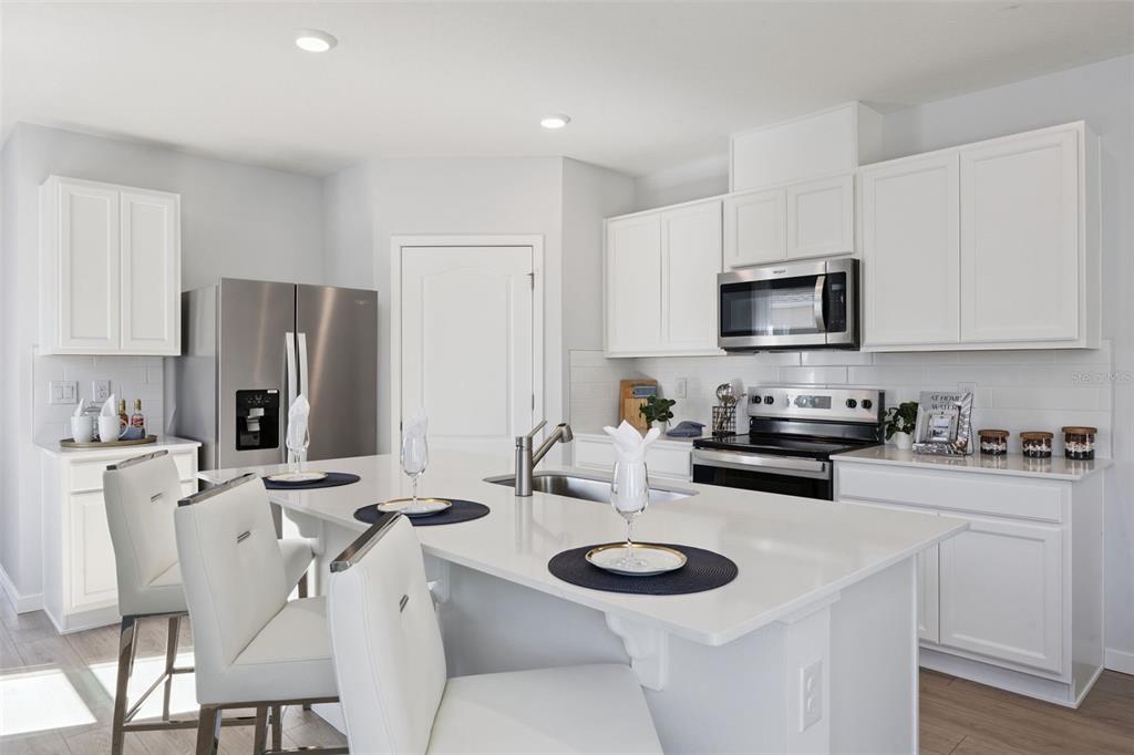3019 House Finch Road St. Cloud, FL 34773 - Photo 9 of 54 a kitchen with stainless steel appliances kitchen island granite countertop a sink a stove a refrigerator cabinets and chairs