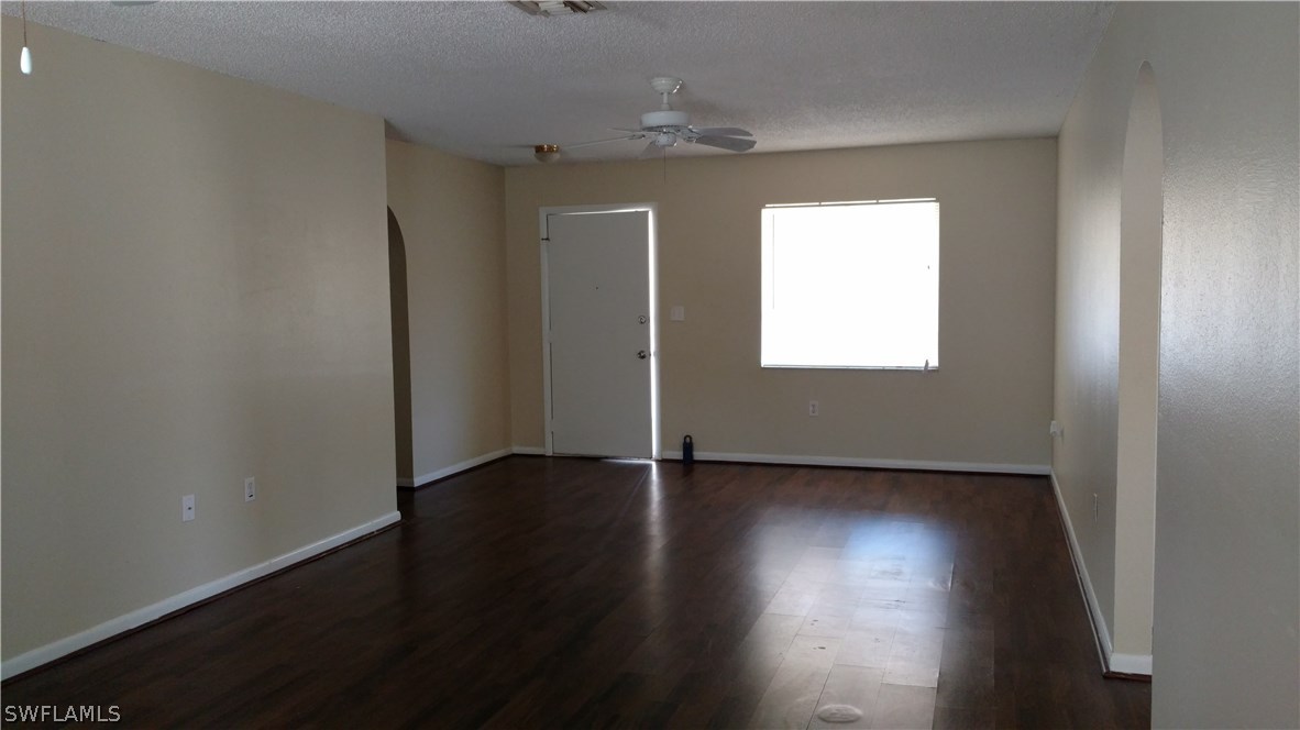 7550 Garry Road Fort Myers, FL 33967 - Photo 5 of 23 an empty room with wooden floor chandelier fan and windows
