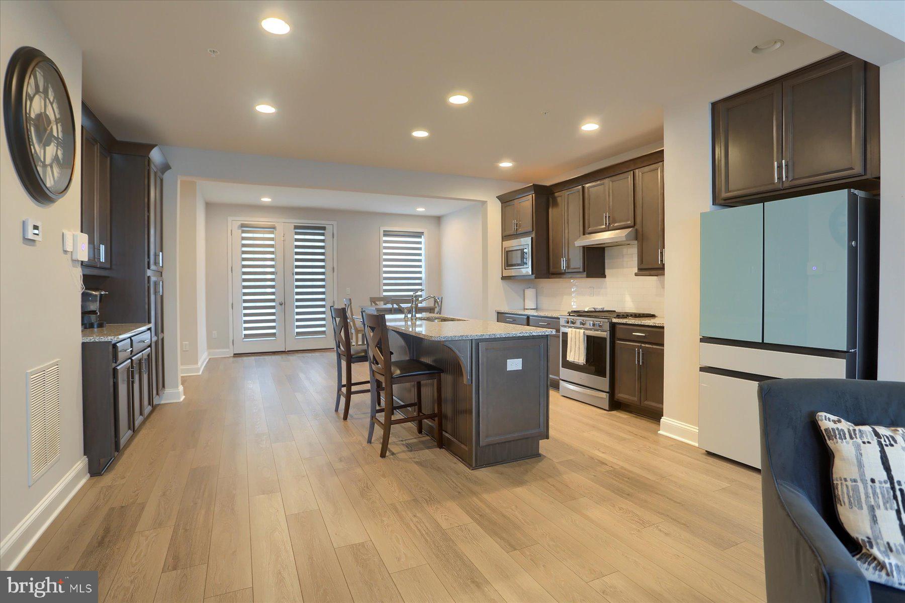 3219 Wayland Road Mechanicsburg, PA 17055 - Photo 11 of 38 a kitchen with stainless steel appliances granite countertop a stove top oven a sink a dining table and chairs with wooden floor