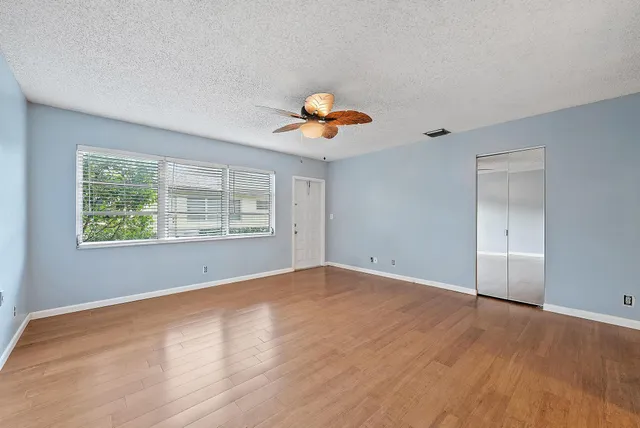 a view of an empty room with window and wooden floor