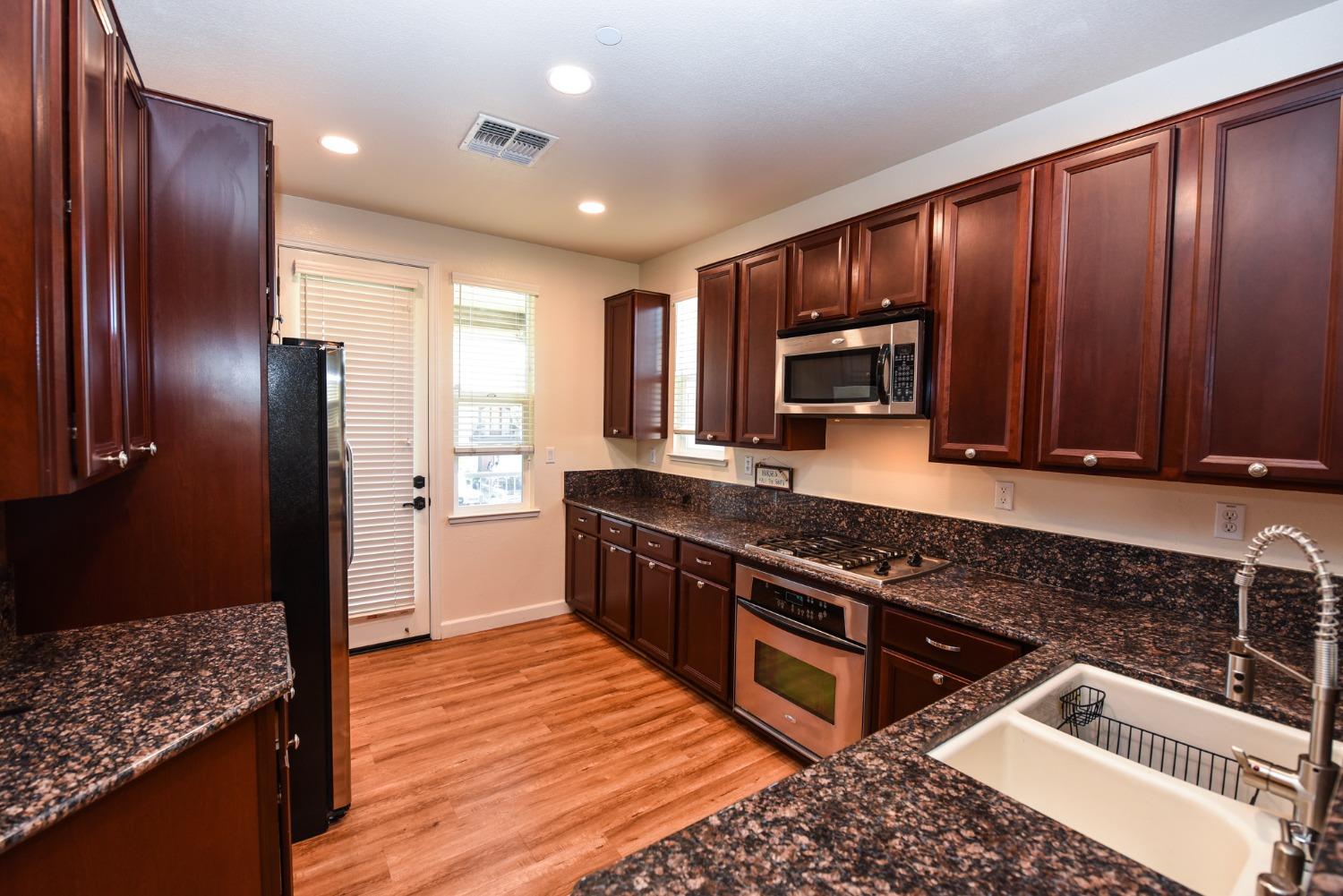 a kitchen with stainless steel appliances granite countertop wooden cabinets a refrigerator and a sink