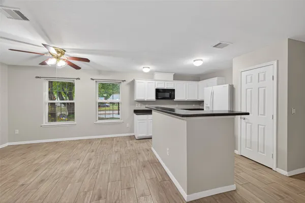 a kitchen with stainless steel appliances granite countertop a refrigerator a stove top oven a sink dishwasher and white cabinets with wooden floor