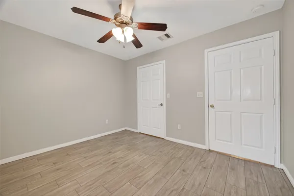 an empty room with wooden floor chandelier fan and closet area with wooden floor