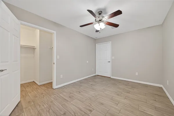 an empty room with wooden floor and ceiling fan