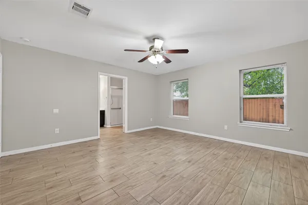 a view of an empty room with a window and wooden floor