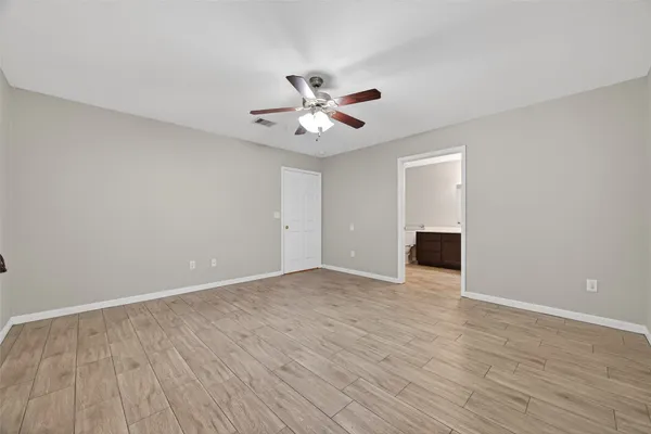 a view of an empty room with chandelier fan and wooden floor