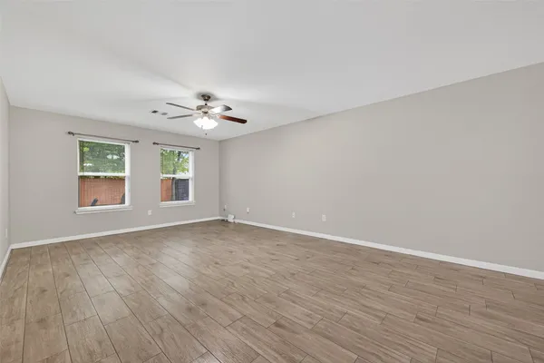 a view of an empty room with a window and wooden floor