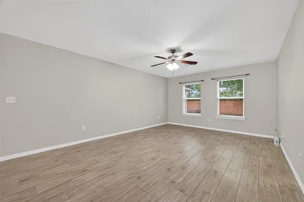 a view of an empty room with a window and wooden floor
