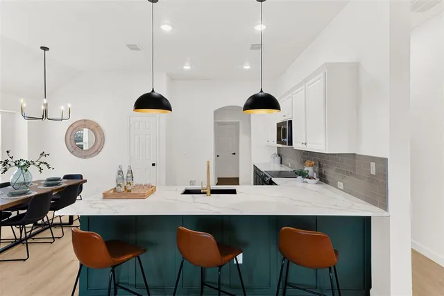 a kitchen with a dining table chairs and sink
