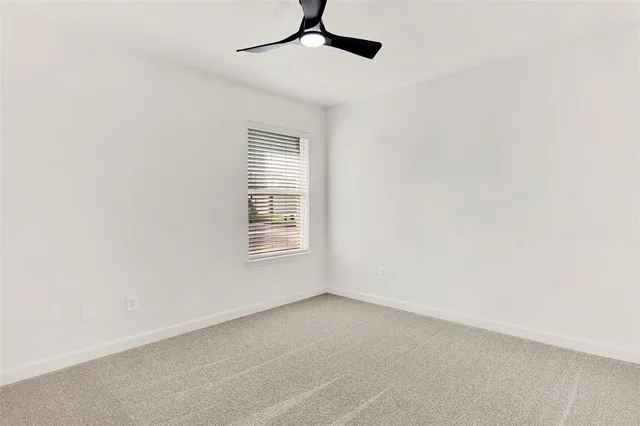 an empty room with a window and a ceiling fan
