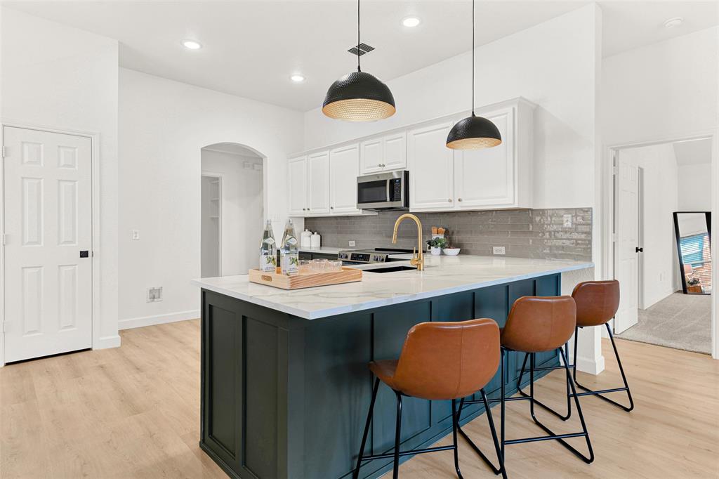 3601 Cottonwood Road Melissa, TX 75454 - Photo 3 of 36 a kitchen with stainless steel appliances granite countertop a sink a stove a kitchen island with chairs and white cabinets