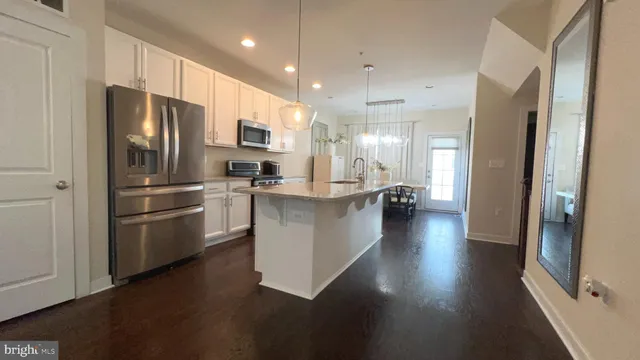 a kitchen with stainless steel appliances kitchen island granite countertop a refrigerator oven a sink dishwasher and a stove with wooden floor