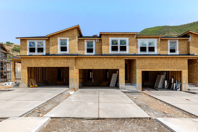 5339 South Acacia Drive, Unit 722 Mapleton, UT 84664 - Photo 1 of 5 Three-unit townhome structure under construction, featuring multiple large window openings, attached garages, and concrete driveways